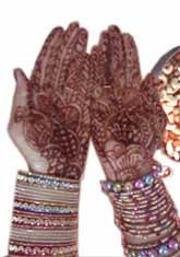 A woman wearing Jewellery and hands decorated with Henna during Karwa Chauth.
